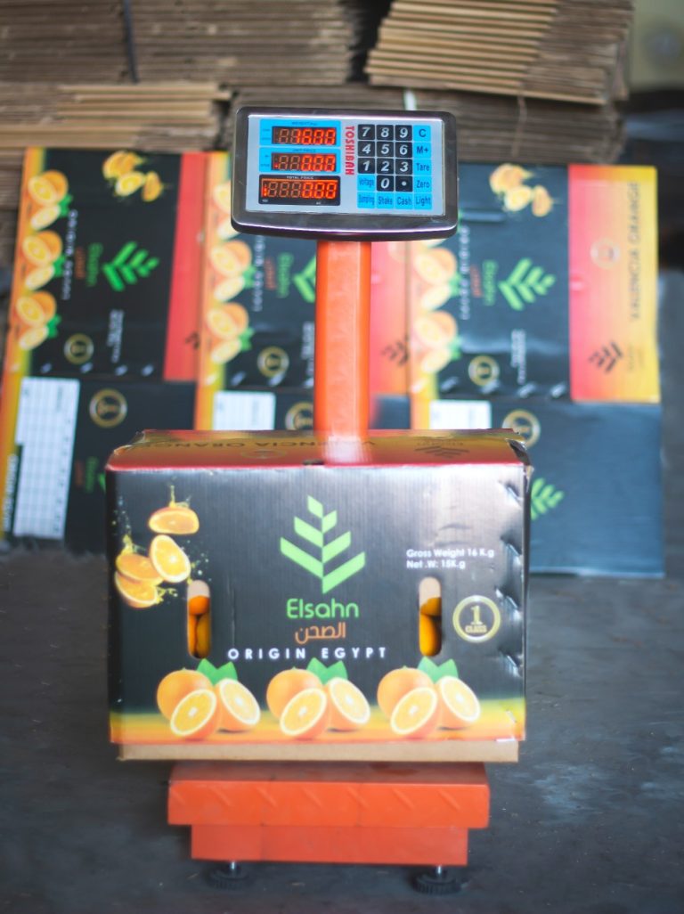 A packed Elsahn Greens orange carton being weighed
