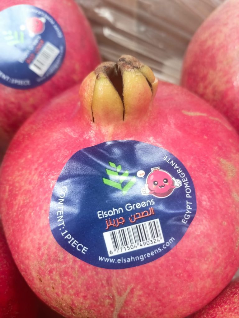 A pomegranate carrying the Elsahn Greens fruit label