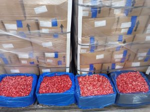 IQF diced strawberries in blue-lined crates beside pallets of packed cartons